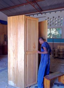 Kujali International Media - Image of Suma, a school administrator, checking out a large wooden cabinet that she is considering to purchase for the school.