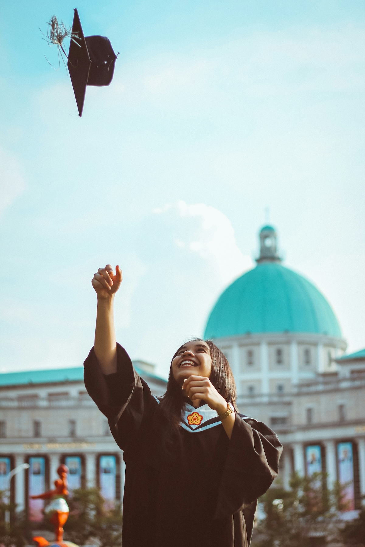 Kujali International Media - Image of a graduate throwing a cap into the air.